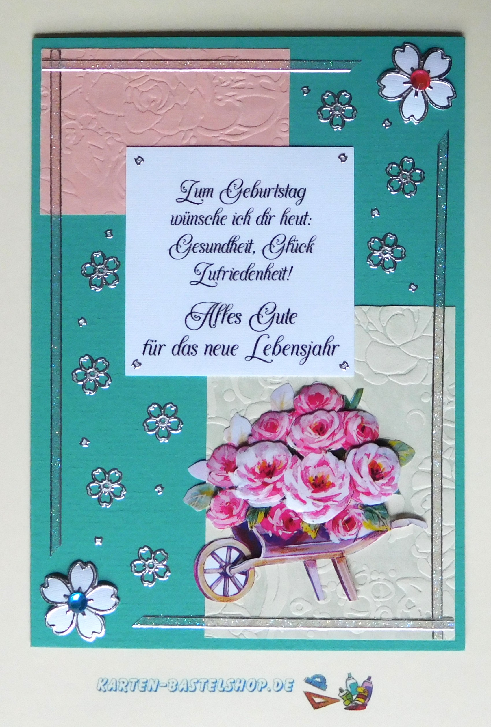 Geburtstagskarte in Türkis mit rosa und elfenbeinfarbenen Flächen, Blütenstickern und Schubkarrenmotiv