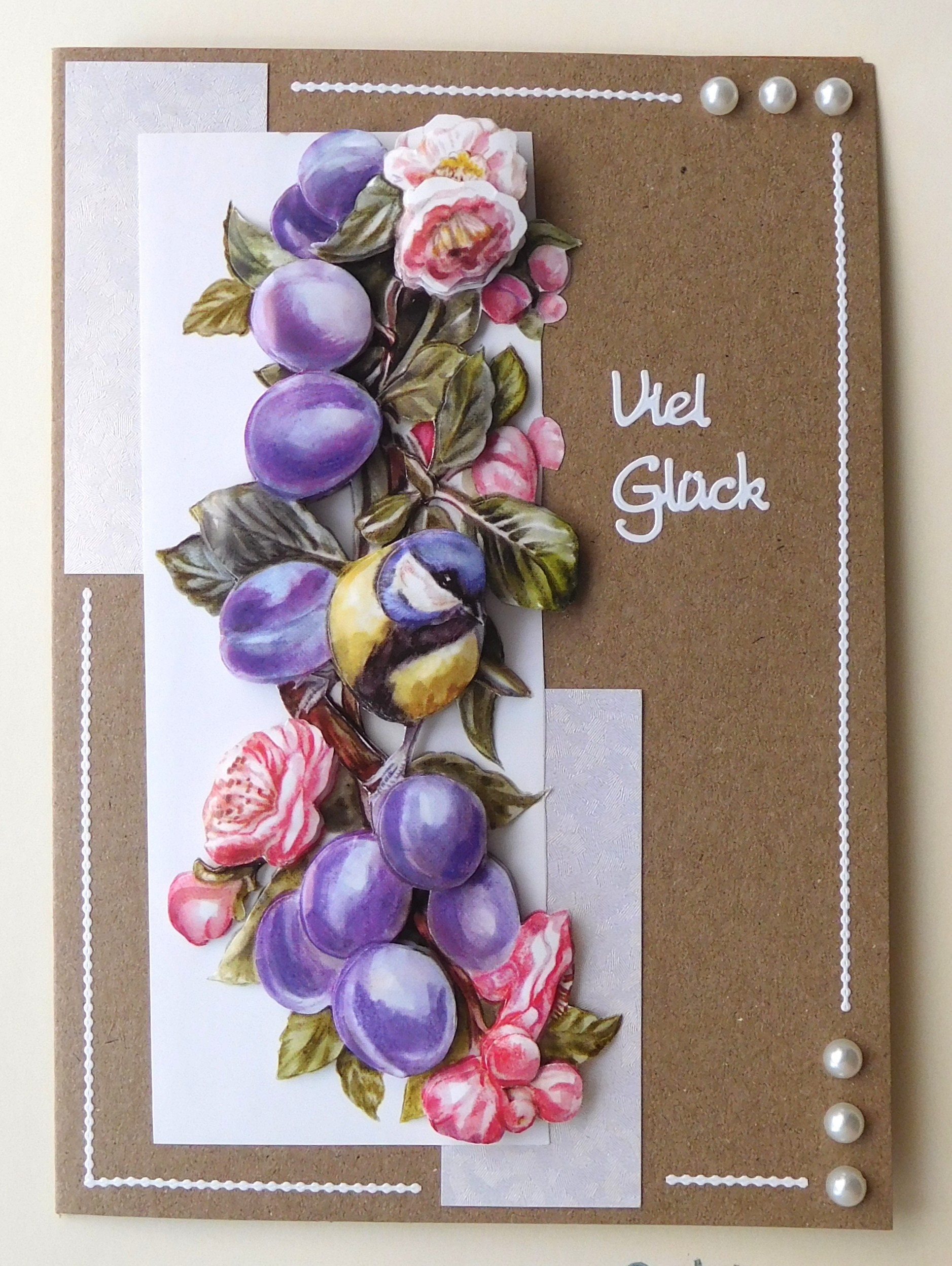 Glückwunschkarte mit Pflaumen, rosa Blüten, kleinem Vogel und dem Gruß Viel Glück